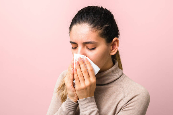 stop spreading coronavirus. young sick woman with fly or virus sneezing and coughing in a mask or napkin looking very hopeless. - Photo, Image