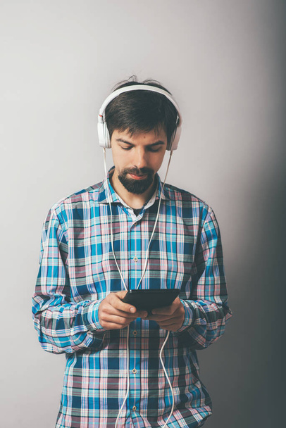 bearded hipster listening to music on headphones with the phone - Photo, image