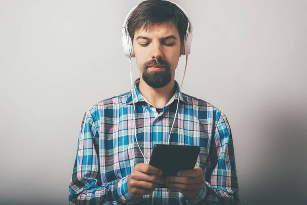 bearded hipster listening to music on headphones with the phone - Foto, afbeelding