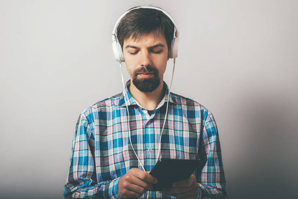 bearded hipster listening to music on headphones with the phone - Foto, Imagen