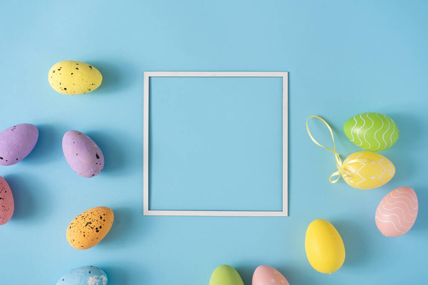 Easter layout made with colorful Easter eggs and pastel blue background. Minimal nature background. Spring holidays concept. Creative copy space. Flat lay. - 写真・画像