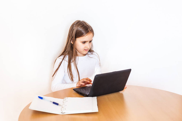 girl during the quarantine does homework using a laptop, tablet and the Internet, studying material, school, remote, learning from home, work, communication via the Internet, friends - Φωτογραφία, εικόνα