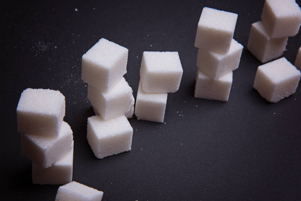Pile of sugar cubes on a black background. - Photo, Image