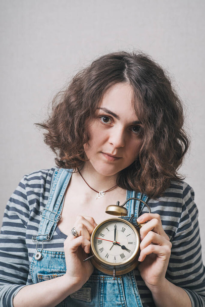 beautiful woman holding alarm clock in hand, dressed in a suit - Foto, afbeelding