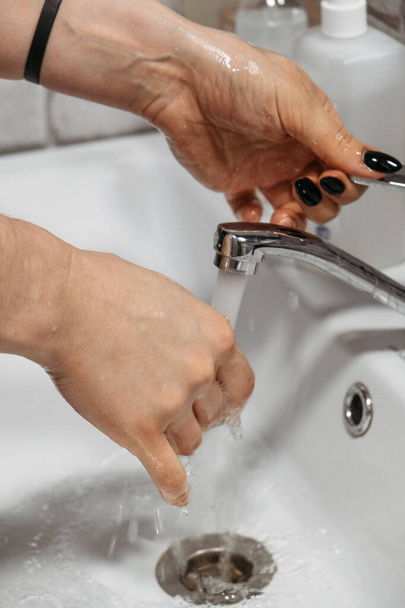 Käsihygienia. Miten pestä kädet saippualla ja vedellä. Naiset pesevät kädet antibakteerisella saippualla kotona kylpyhuoneessa. Bakteerien leviämisen estäminen
 - Valokuva, kuva