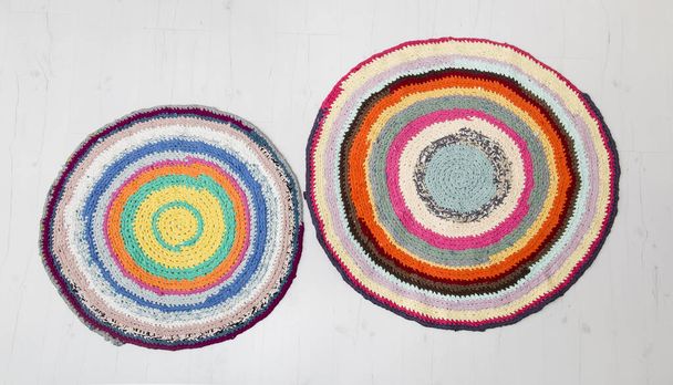 Colorful crochet rug from repurposed T-shirts at white wooden home floor. Flat lay view. - Photo, Image
