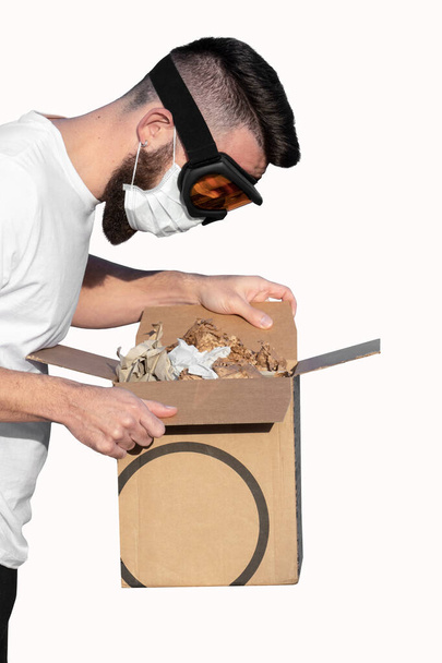 Homme portant des lunettes de protection et masque facial déballage boîte en carton sur fond blanc. Livraison sans contact pendant la pandémie de coronavirus Covid-19 concept
 - Photo, image