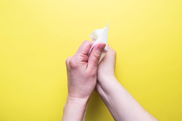 Hands are wiped with a damp antibacterial cloth. The concept of hand cleanliness and the fight against virus microbes. Yellow background - Foto, imagen
