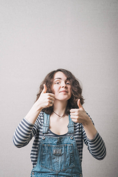 Woman showing two thumbs up. On a gray background. - Foto, imagen