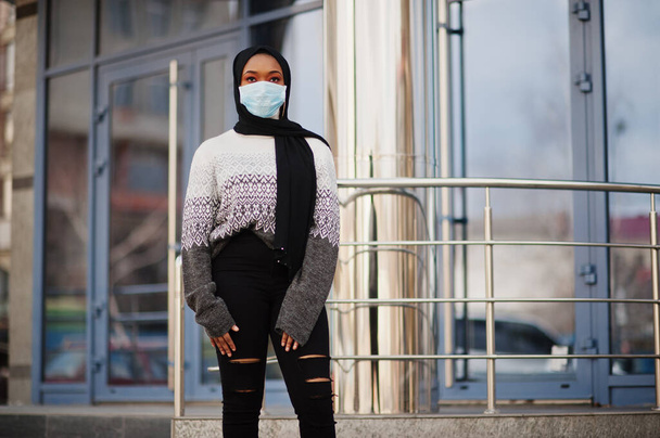 African muslim young volunteer woman wearing face mask and black hijab outdoors. Coronavirus quarantine and global pandemic. - Фото, зображення