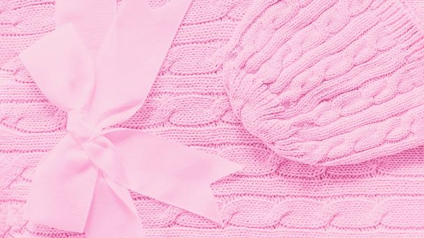 Sombrero de punto bebé sobre una suave manta rosa. Lindo regalo para bebé recién nacido con lazo. Copiar espacio, 16 en 9 formato panorámico
 - Foto, imagen