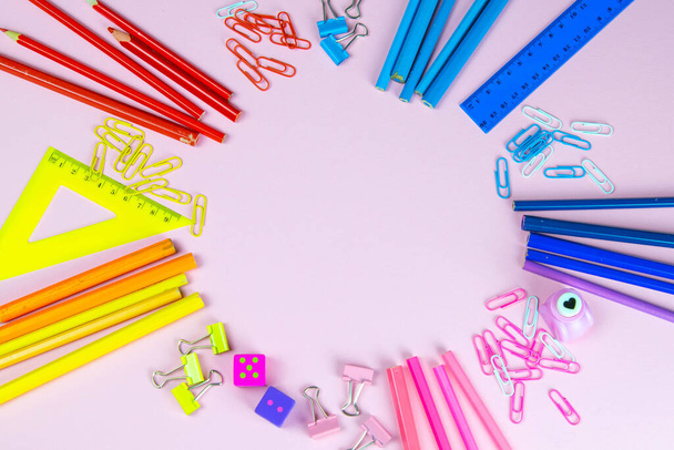 Lápices multicolores reglas, bolígrafos, lápices y tijeras y papelería de pie sobre un fondo rosa
. - Foto, Imagen