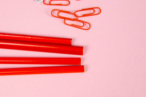 Többszínű piros ceruzák vonalzók, tollak, ceruzák és ollók és írószerek állnak rózsaszín alapon. - Fotó, kép
