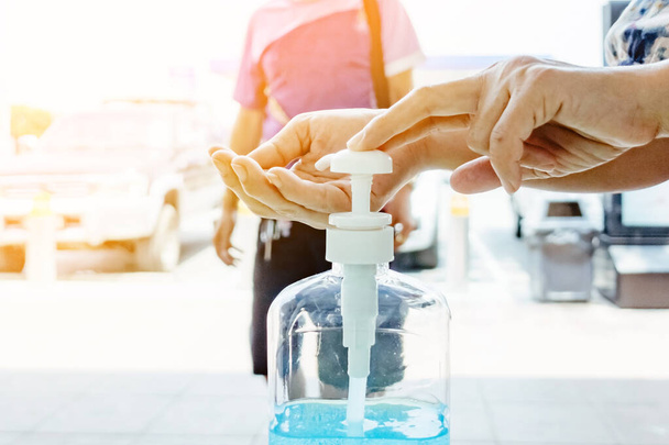 Woman uses her hand to press hand sanitizer bottle to clean her hand at wayside in the city. Concepts of Flu virus, Covid-19 (Coronavirus disease). Selective focus on alcohol gel bottle. - Fotó, kép