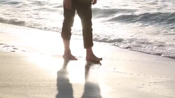 裸足でズボンを履いたビジネスマンが海岸沿いを歩いている。オフィスの服を着た男が海のビーチを歩いていて、湿った砂と水の上を歩いている. - 映像、動画