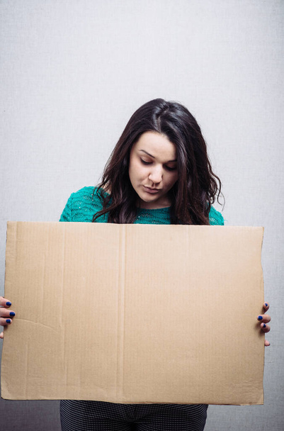 woman with empty cardboard. On a gray background. - Foto, Bild