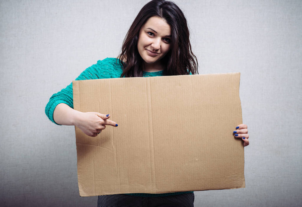 woman with empty cardboard. On a gray background. - Фото, изображение