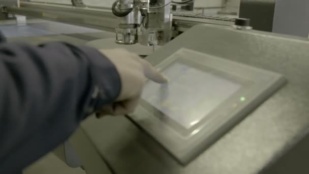 Een productiearbeider zet een moderne machine op met een touchpad. - Video