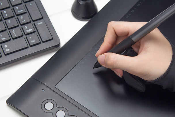 Graphic designer working on digital tablet. The hand draws on a graphics tablet. Freelance, designer, Illustrator. Technology, remote work, outsourcing. Glove and pen for a graphic tablet. Project - Photo, Image