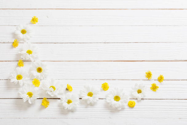 white chrysanthemum and yellow coltsfoot on white wooden background - Fotó, kép