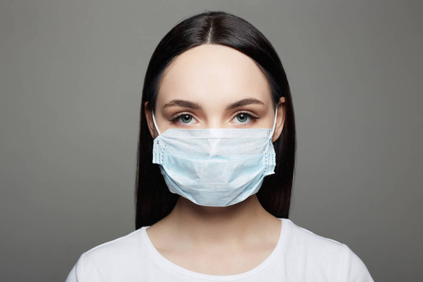 Jonge vrouw in masker. Epidemisch concept. Coronavirus. medisch gemaskerd mooi meisje. - Foto, afbeelding