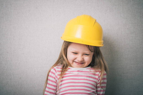 Brunette little girl with a yellow helmet  - Foto, imagen