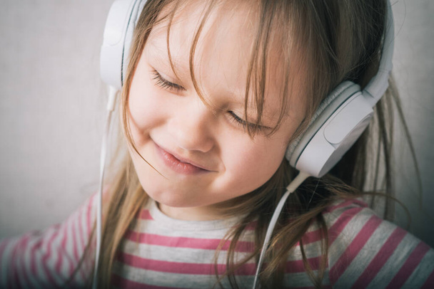 Beautiful cute happy little girl with headphones - Фото, изображение