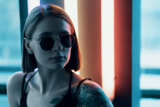 Fashion portrait of young attractive girl in sunglasses. Neon light - Фото, изображение