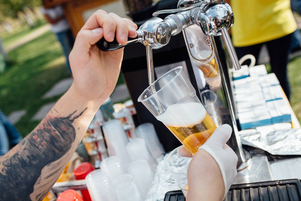 mano del barman versa birra alla spina da un rubinetto in un bicchiere su un pic-nic all'aperto
 - Foto, immagini