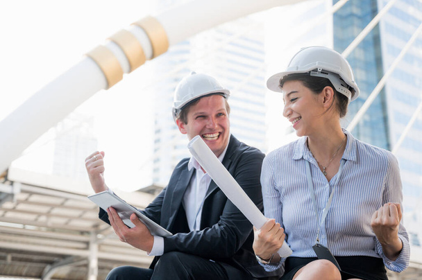 Portrait of civil engineers man and woman with tablet doing thinking, planning on construction building background and feeling happy. - Photo, Image