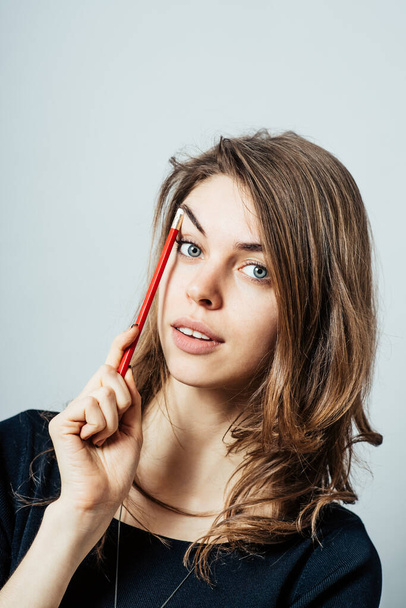 Pretty brunette girl thinking holding a pencil at a temple - Foto, afbeelding