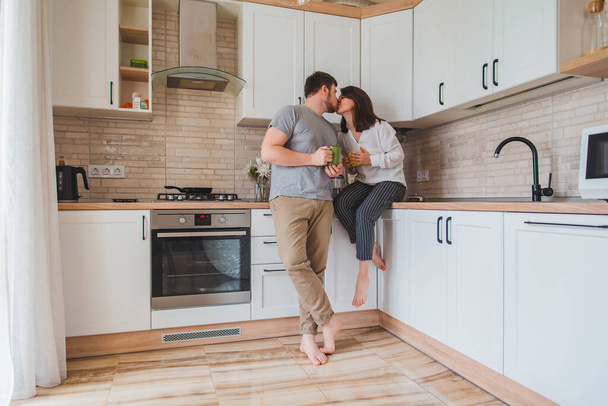 young couple kissing on kitchen while drinking tea. young family - Foto, immagini