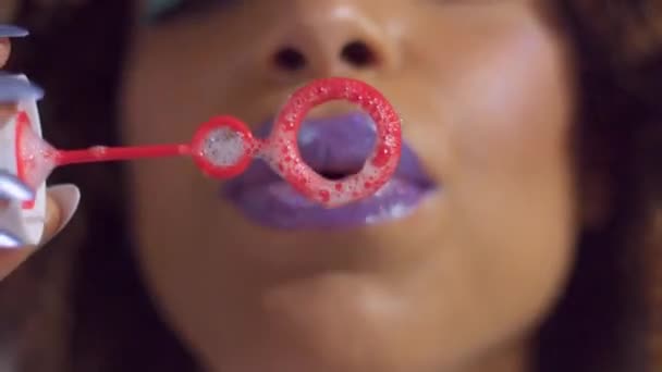 Mulher de raça mista com batom brilhante violeta em golpes para soprador de bolhas em direção à câmera
 - Filmagem, Vídeo