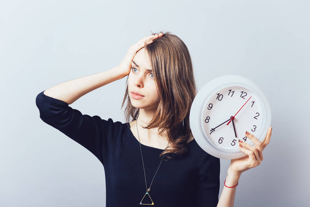 Shocked woman holding a clock - Фото, изображение