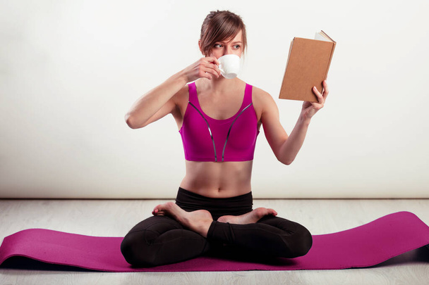 Vita sana - donna che medita. Fitness donna che pratica yoga a casa rilassarsi leggendo un libro e bevendo caffè. Godere la pace e la serenità in Lotus posa
 - Foto, immagini