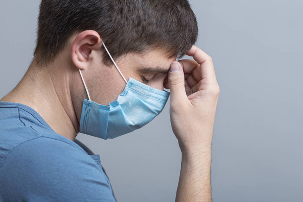 upset young doctor in protective medical mask thinking about problem on gray studio background, concept medicine and health,exhaustion at work - Photo, Image