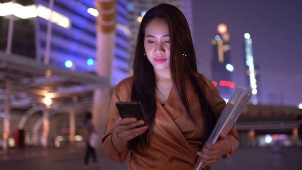 Piękny biznes młoda azjatycka kobieta spacery w nocy ulice miasta za pomocą smartpone - Zdjęcie, obraz