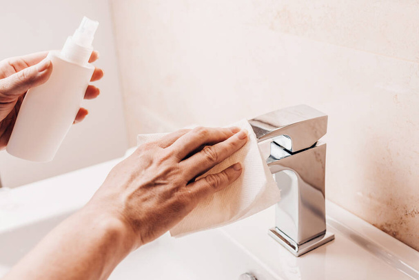 Sanitary treatment - a woman applies an alcohol-based antiseptic spray to a water tap to prevent the spread of the virus - Φωτογραφία, εικόνα