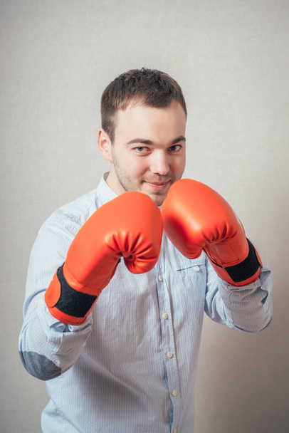 Businessman ready to fight with boxing gloves over gray background. Looking at camera - Фото, изображение