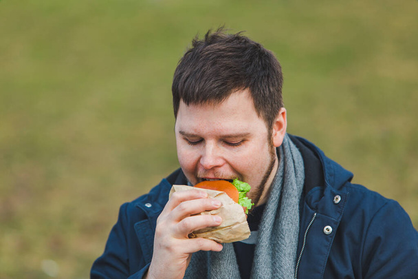 young adult man eating hamburger. portrait - Фото, зображення