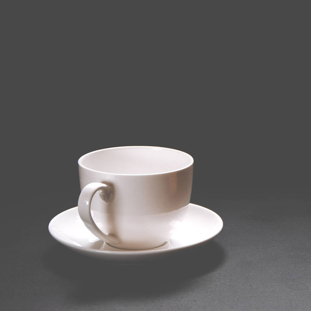 Biały ceramiczny kubek do kawy stoi na czarnym tle. Zbliżenie - Zdjęcie, obraz