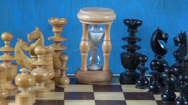 Wooden chess pieces on chessboard and sandglass - Footage, Video