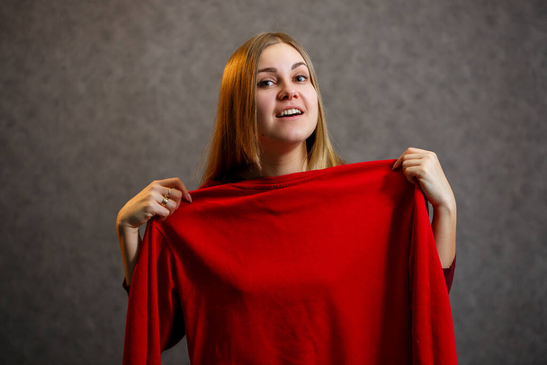 mooi meisje probeert op een rode trui - Foto, afbeelding