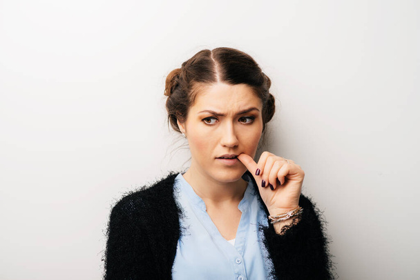 Γυναίκα σκέφτεται με ένα δάχτυλο στο στόμα του, πονηρή, απελπισμένη. Απομονωμένα σε λευκό φόντο - Φωτογραφία, εικόνα