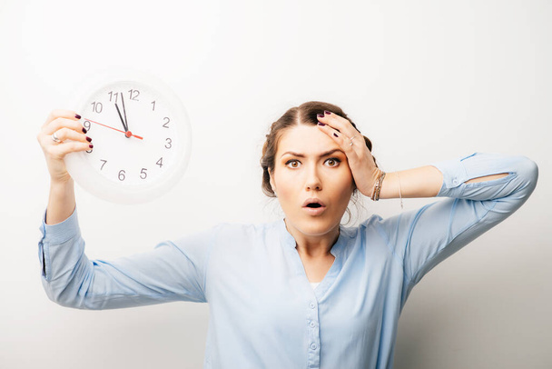 Woman with clock and hand on head dissatisfied, angry late. Isolated on a white background - Foto, afbeelding
