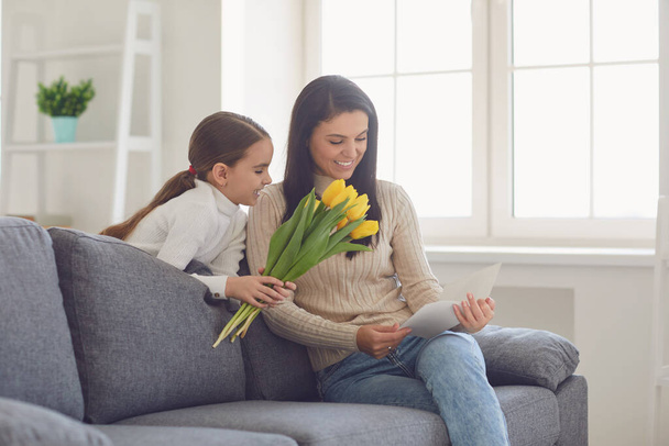 Happy mothers day. Daughter congratulates hugs his mother holds a bouquet of flowers in the room. - Foto, Bild