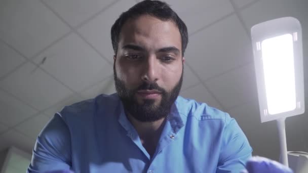 Patient point of view of handsome Middle Eastern dentist manipulating. Portrait of serious confident male stomatologist working in dental clinic. Medicine, dentistry, close-up. - Video