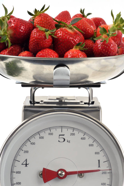 Erdbeeren auf Küchenwaage in Großaufnahme auf weißem Hintergrund  - Foto, Bild