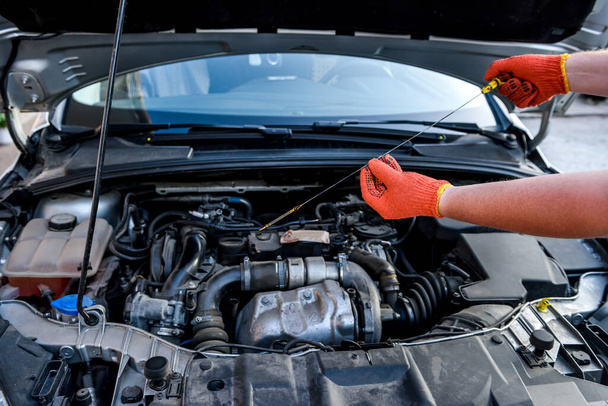 Emberi kéz olajszintmérővel az autó motorja ellen - Fotó, kép