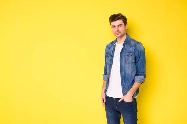 cool handsome young men in jeans outfit standing on yellow background - Foto, afbeelding